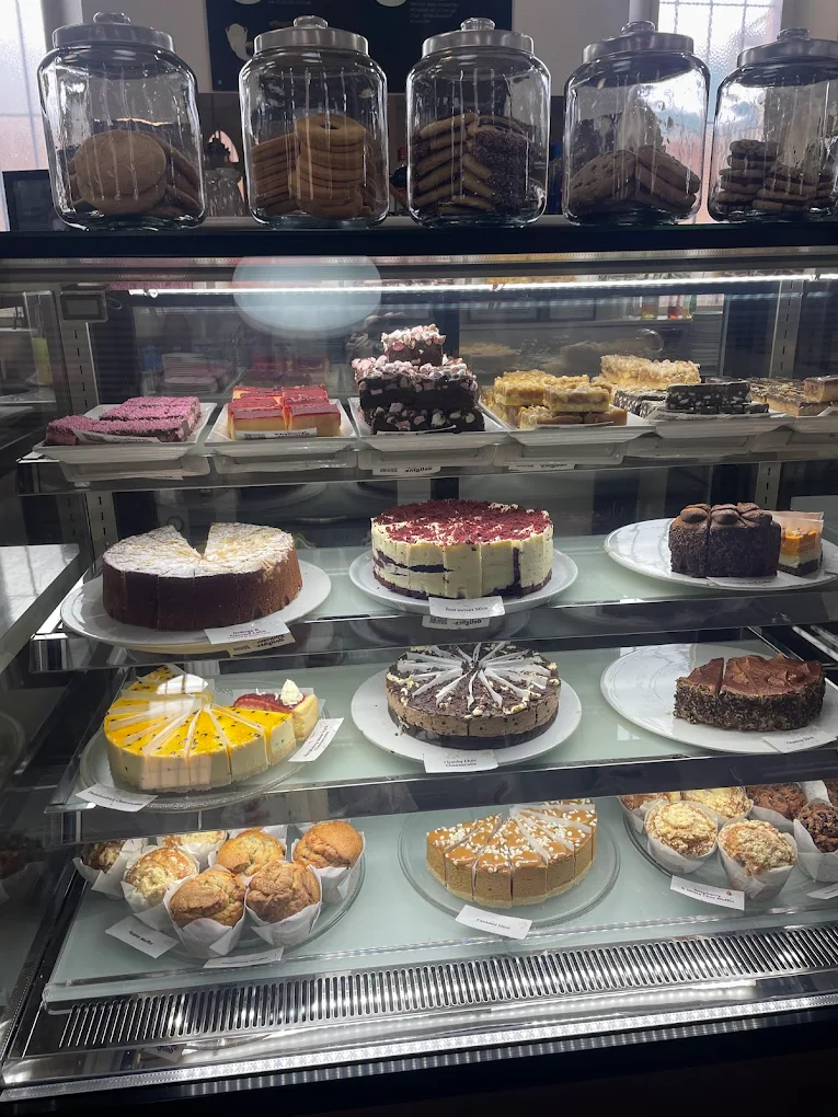 Display fridge full of cakes, slices, muffins and jars of biscuits at Cafe Safavi